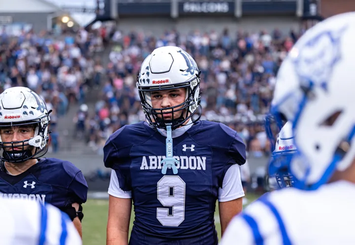 A helmeted football player wearing number 9 stands among teammates before the game.