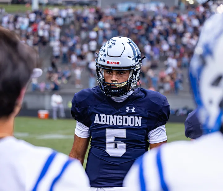 A helmeted football player wearing number 6 looks ahead between teammates.