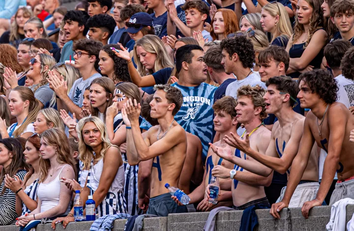 A dense crowd of students cheers during a football game.