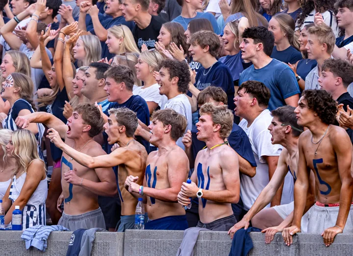 Students clap and cheer together in the football grandstand.