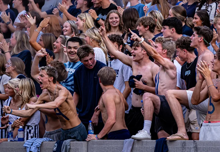 Students smile, cheer, and embrace in the football stands.