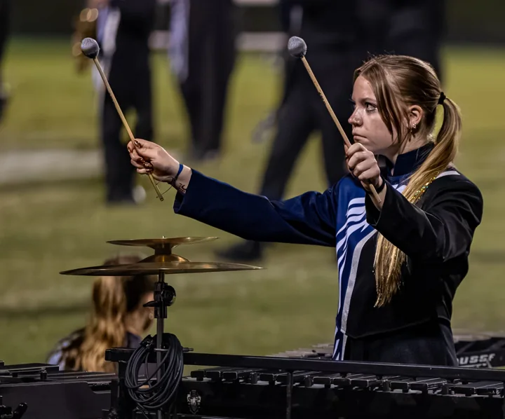 A percussionist holds mallets above a keyboard percussion instrument.