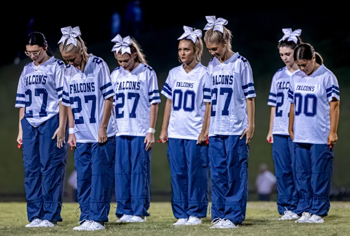 A group of performers in football-style jerseys stands in formation on the field.