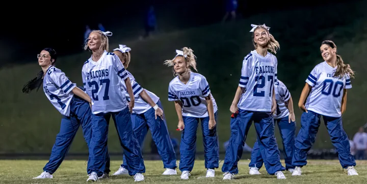 Performers in matching jerseys and blue pants move together across the field.