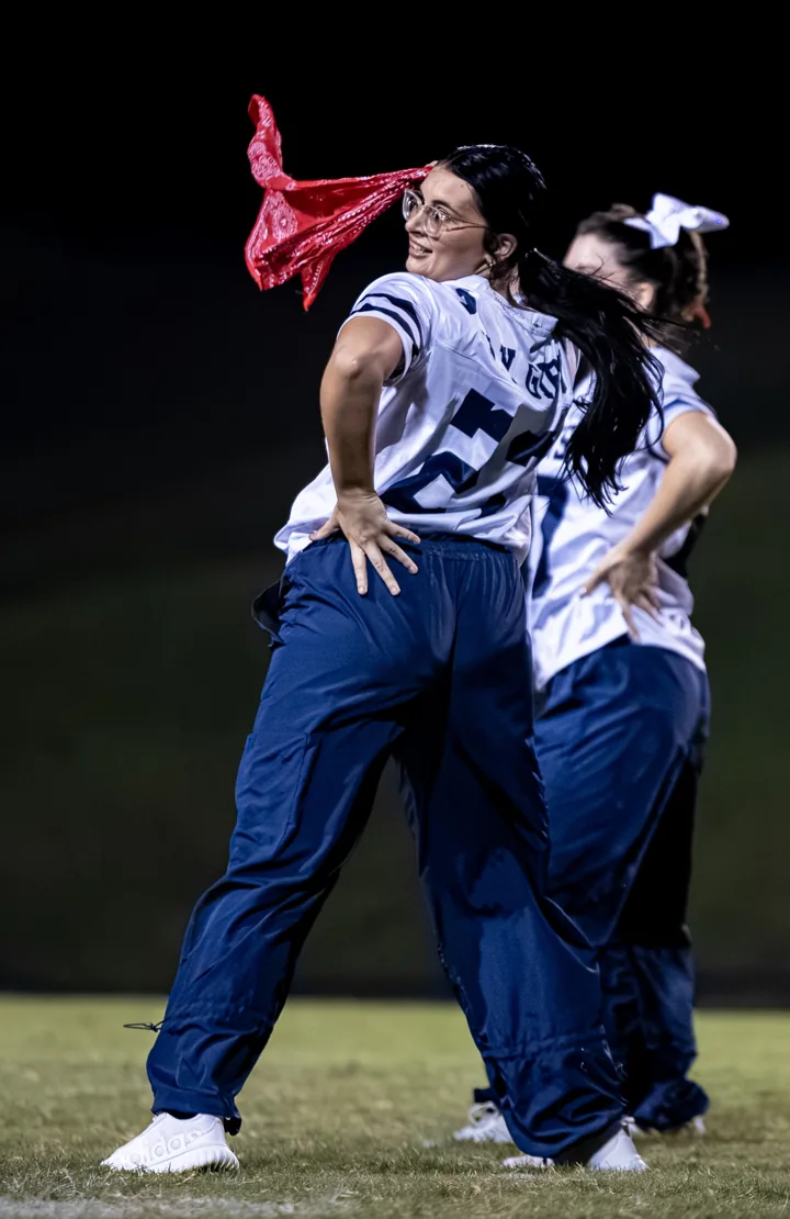 A performer in a football-style jersey turns with a red scarf during a routine.