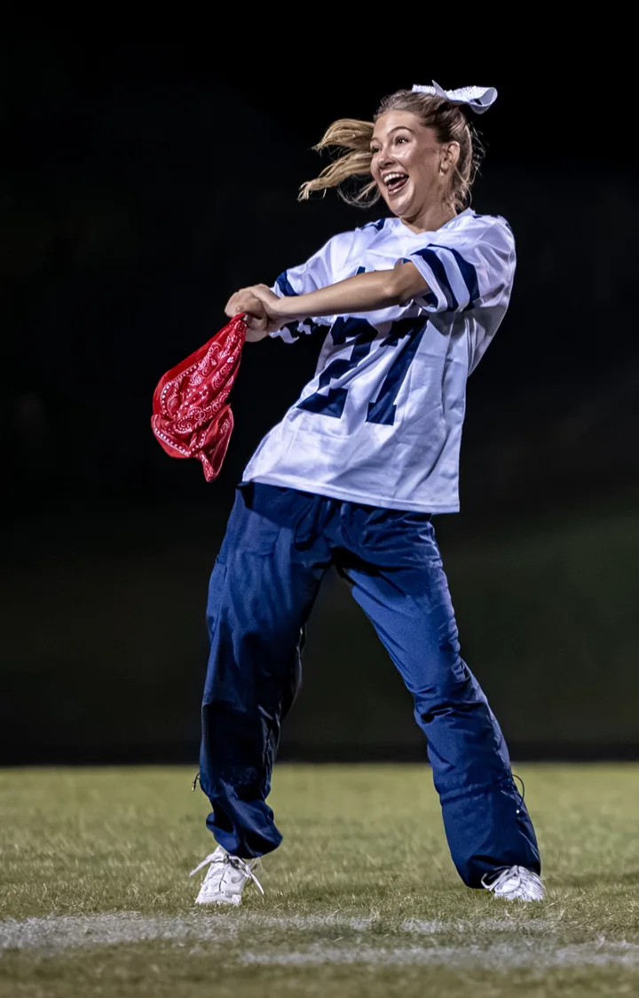 A performer extends a red scarf while moving through a field routine.