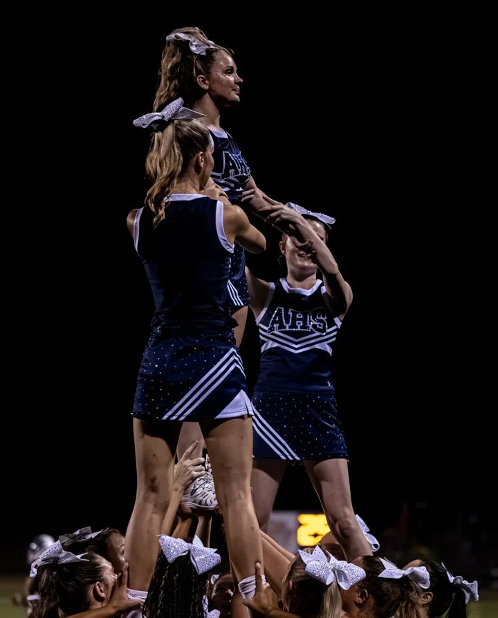 Cheerleaders support teammates above the crowd during an evening stunt.