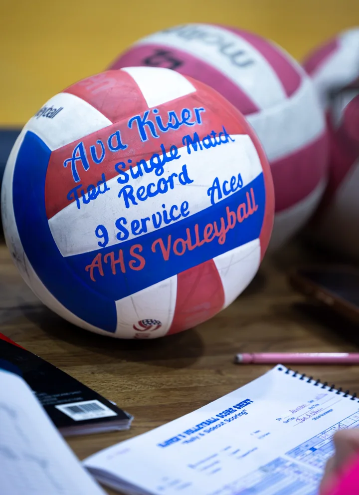 A signed volleyball rests beside papers on a scorer’s table.