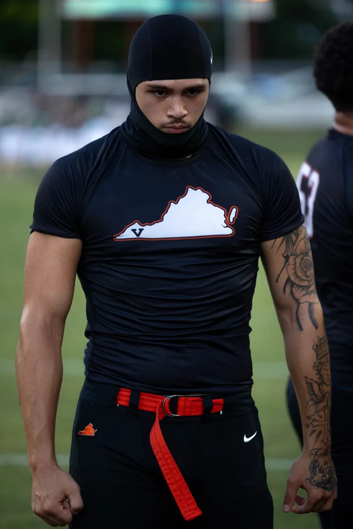 An athlete in a black warm-up shirt and head covering stands on the field.