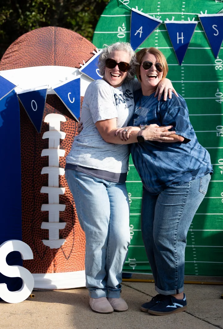 Two people laugh together while posing at an outdoor photo backdrop.